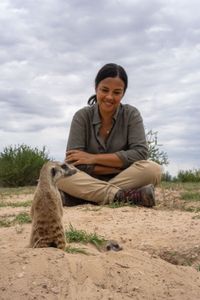 Liz Bonnin watches as a three-week-old meerkat pup emerges from the den for the first time. (National Geographic/Emilie Ehrhardt)