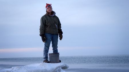 Sue Aikens gathers salt water while standing on the edge of the Arctic Ocean. (BBC Studios/Michael Cheeseman)