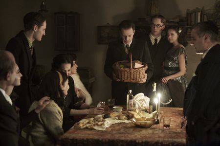A SMALL LIGHT - The Frank, van Pels, and Gies families celebrate Hanukkah in the upcoming limited series A SMALL LIGHT, from National Geographic and ABC Signature in partnership with Keshet Studios. From left: Liev Schreiber as Otto Frank, Ashley Brooke as Margot Frank, Rudi Goodman as Peter van Pels, Billie Boullet as Anne Frank, Amira Casar as Edith Frank, Caroline Catz as Mrs. van Pels, Noah Taylor as Dr. Pfeffer, Joe Cole as Jan Gies, Bel Powley as Miep Gies, and Andy Nyman as Mr. Van Pels. (Photo credit: National Geographic for Disney/Dusan Martincek)