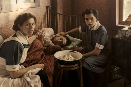 A SMALL LIGHT - Nurses Liesje and Betje care for Kuno as seen in A SMALL LIGHT. (From left: Sarah Winter as Liesje, Preston Nyman as Kuno, and Hannah Bristow as Betje). (Credit: National Geographic for Disney/Dusan Martincek)