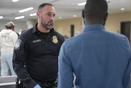 CBP Officer Mccants looks on while a passenger talks with a fellow officer in Atlanta, Ga. (National Geographic)