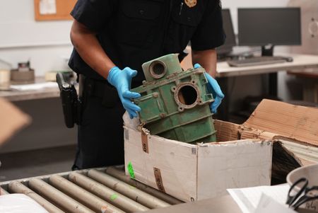 CBP Supervisory Officer Keller extracts a machine part out of a shipment box to inspect it for contraband in Philadelphia. (National Geographic)