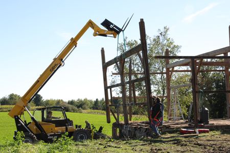 Ben Reinhold operates a telehandler while Charles Pol instructs him as they dismantle the frame of the old barn. (National Geographic)