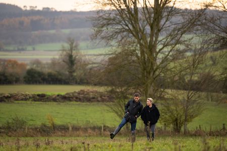 Antoni Porowski and Florence Pugh walk through a field in Yorkshire. (National Geographic/Chris Raphael)