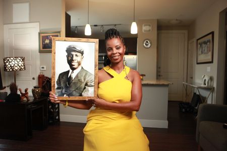 Erika Bethea holds a portrait of her grandfather, Clark Simmons, in her home in Plano, Texas. "Erased: WW2's Heroes of Color" tells the stories of three Black heroes who miraculously survived the attack on Pearl Harbor. One of these men was Clark Simmons, who served as mess attendant on the USS Utah. (National Geographic/Nelson Adeosun)