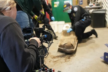 A cameraman films multiple CBP officers work to dismantle the gas tank of a suspect's vehicle after packages of suspected narcotics were seen on a camera scope in Calexico, Calif. (National Geographic)