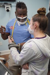 Dr. Hodges has a nervous vet tech, Savanna Phelps, help him with a speckled king snake during a health certificate exam. (National Geographic for Disney/Sean Grevencamp)