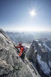 Alex Honnold climbing up the Devil's Thumb with the rest of the traverse behind him and the sun above him.  (National Geographic/Renan Ozturk)