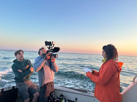 BTS of Diva Amon speaking into the camera on the boat with Martin Cass directing the scene. (National Geographic/Verity Thomson)