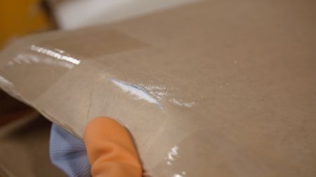 CBP Officer Kelleher inspects the inner lining of a shipped cardboard box and discovers a powder suspected to be narcotics at the JFK International Airport in New York. (National Geographic)