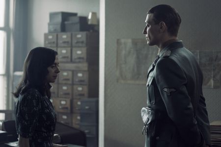 A SMALL LIGHT - Miep, played by Bel Powley, speaks with Silberbauer, played by Daniel Donskoy, in the Opekta office as seen in A SMALL LIGHT. (Credit: National Geographic for Disney/Dusan Martincek)