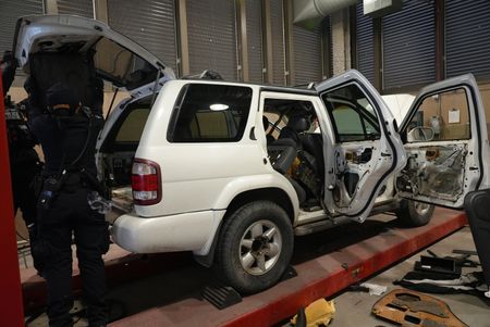 CBP Officers Hernandez and Hoffman work to dismantle the trunk of a suspect's vehicle in search of smuggled drugs in Calexico, Calif. (National Geographic)