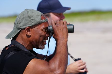 Christian Cooper and NYC Plover Project founder Chris Allieri look at a piping plover through binoculars at Fort Tilden. (National Geographic/Troy Christopher)