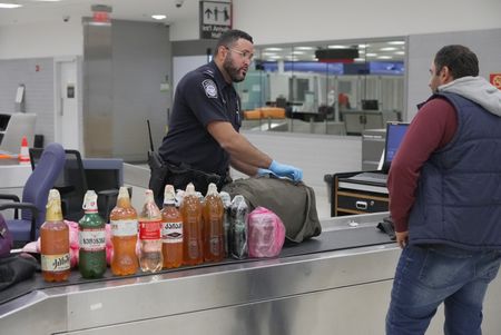 Bottles of homemade wine are seen on an inspection table while CBP Officer De La Cruz questions a traveler and inspects their luggage at the Philadelphia International Airport in Philadelphia, Pa.  (National Geographic)