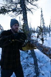 Johnny Rolfe sets a conibear trap on a tree before the trapping season comes to an end. (BBC Studios Reality Productions, LLC/Tyler Colgan)