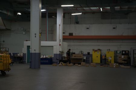 CBP Agriculture Specialist Joseph lays out shipped packages on the ground, so his K9 can inspect them for possible contraband in the JFK Mail Facility at the JFK International Airport, in New York. (National Geographic)