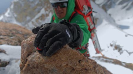 Jimmy Chin reaches for a hold as he climbs a mountain with skis on his back.  (credit: Jimmy Chin Productions)