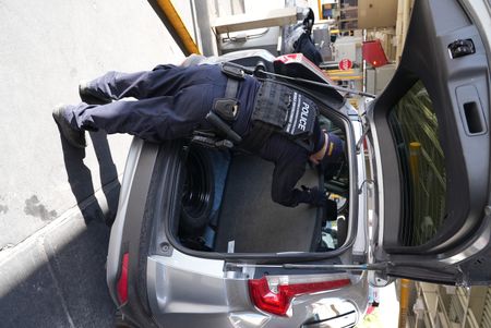 A CBP officer inspects the trunk of a passenger's vehicle for hidden contraband in El Paso, Texas. (National Geographic)