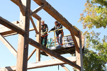 Ben Reinhold and Charles Pol, on a lift, plan out how to carefully take down the beams from the old barn. (National Geographic)