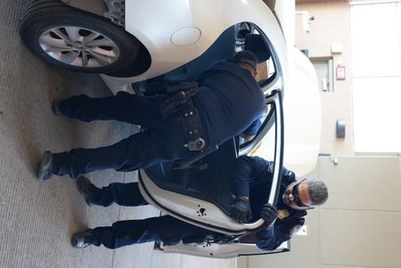 Two CBP officers work on dismantling the right rear passenger door of a suspect's vehicle to find hidden contraband in El Paso, Texas. (National Geographic)