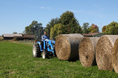 Charles Pol uses a blue tractor to transport large bales of hay at the Pol family's farm. (National Geographic)