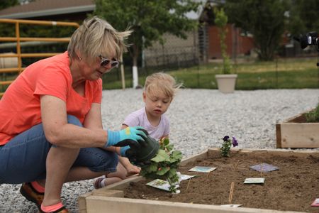 Judi Reinhold and Abigail Pol replant vegetables in the new garden at the Pol family's farm. (National Geographic)
