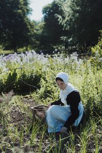 Geillis Duncan crouches in a field, with a basket in arm, harvesting plants and herbs for medicinal properties. (Dash Productions Services LTD/Antoan Ivanov)