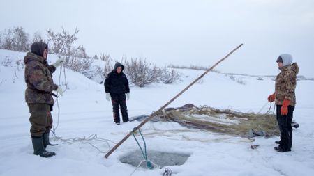 Chip Hailstone sets a fish net under the ice with his daughters, Tinmiaq and Carol Hailstone. (BBC Studios/Dwayne Fowler)