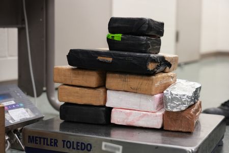 Multiple packages of suspected narcotics are sitting on a scale to be weighed after they were discovered hidden in a suspect's vehicle in Brownsville, Texas. (National Geographic)