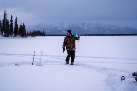 Johnny Rolfe uses an auger to cut through the ice and set his burbot lines. (BBC Studios Reality Productions/Patrick Henderson)