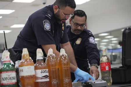 CBP Officers De La Cruz and Nikirk test the contents of homemade wine found in a traveler's luggage with a Gemini machine at the Philadelphia International Airport in Philadelphia, Pa.  (National Geographic)