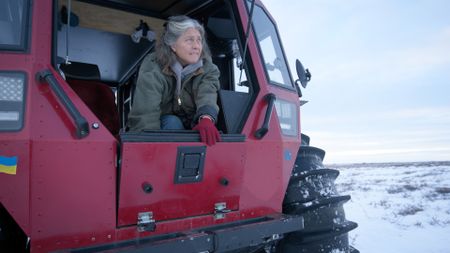 Sue Aikens carefully makes her way out of her all terrain vehicle while hunting ptarmigan. (BBC Studios/Michael Cheeseman)