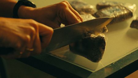 Mariana van Zeller cuts into a bar of hash in Lisbon. (National Geographic)