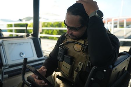 A CBP Agent looks at his phone on a water vessel in Mayaguez, P.R. (Lucky 8 TV/Paul Taggart)