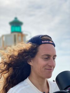 Big wave surfer Justine Dupont smiles in front of a lighthouse as DP Alfredo de Juan films her.  (National Geographic/Gene Gallerano)