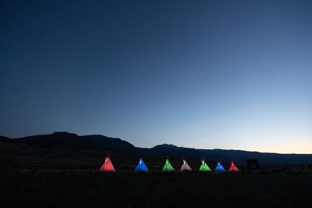 A row of teepees lit up in different colors in front of the 
Roosevelt arch at sunrise.   (National Geographic/Jeff Reed)