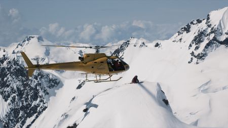 A helicopter lands on top of an Alaskan mountain and a skier hops off.  (mandatory credit:  Teton Gravity Research)