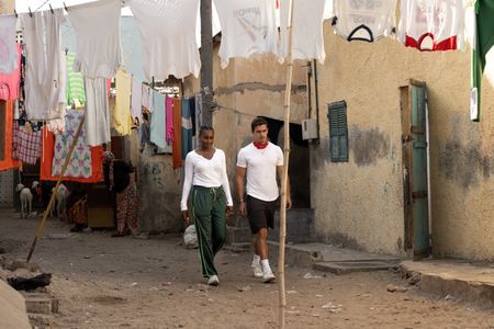 Issa Rae and Antoni Porowski walking through Papa Abdoulaye Sene's compound. (National Geographic/John Wendle)