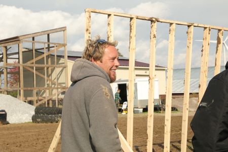 Ben Reinhold smiles next to a wooden frame they transported from the old barn to the Pol family's farm. (National Geographic)