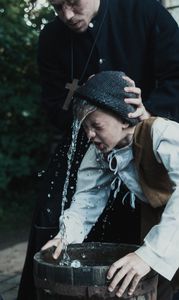 Laurentius Hornaeus, a minister in the town of Torsaker, holds a boy's head over a bucket of water. (Dash Productions Services LTD/Antoan Ivanov)