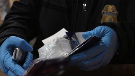 CBP Officer Zuniga holds a package of cocaine after it was discovered smuggled in a shipment at the JFK International Airport in New York. (National Geographic)