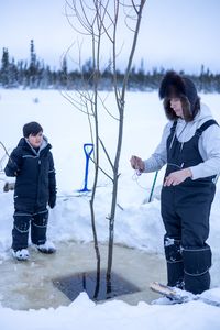 Ricko DeWilde teaches his son Keenan DeWilde how to properly set a beaver trap under the ice. (BBC Studios Reality Productions/v)