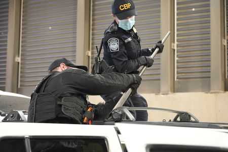 CBP Officers Hernandez and Hoffman work to dismantle the roof rack on a suspect's vehicle in search of smuggled drugs in Calexico, Calif. (National Geographic)