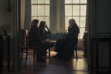 A SMALL LIGHT - Bep, played by Sally Messham, Miep, played by Bel Powley, and Mr. Kleiman, played by Ian McElhinney, talk in the Opekta office as seen in A SMALL LIGHT. (Credit: National Geographic for Disney/Dusan Martincek)