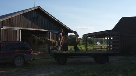 Charles Pol and Ben Reinhold moving the bundles of hay from the trailer to the barn at the Pol family's farm. (National Geographic)