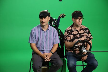 Randy and Jason Sklar sitting Infront of a green screen in golf attire. (National Geographic/Robert Toth)