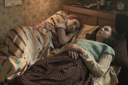 A SMALL LIGHT - Tess, played by Eleanor Tomlinson, talks with Miep, played by Bel Powley, in her bedroom as seen in A SMALL LIGHT. (Credit: National Geographic for Disney/Martin Mlaka)
