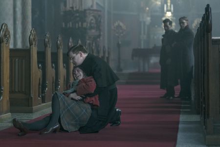 A SMALL LIGHT - Maya, played by Sarah T. Cohen, is consoled by Father Dirksen, played by Ben Esler, as Isaac, played by Dylan Edwards, and Jan, played by Joe Cole, look on, as seen in A SMALL LIGHT. (Credit: National Geographic for Disney/Martin Mlaka)