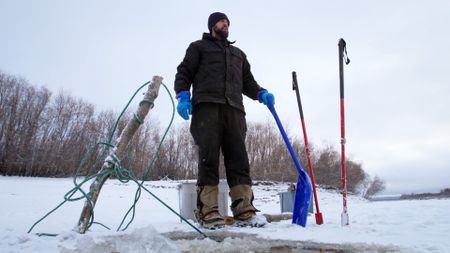 Chevie Roach sets fish nets under the ice for subsistence food. (BBC Studios/Brian Bitterfeld)