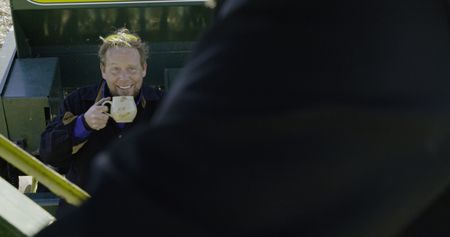 Ben Reinhold smirks at Charles Pol while he drinks from a mug. They are about to attempt to plant the hayfield. (National Geographic)